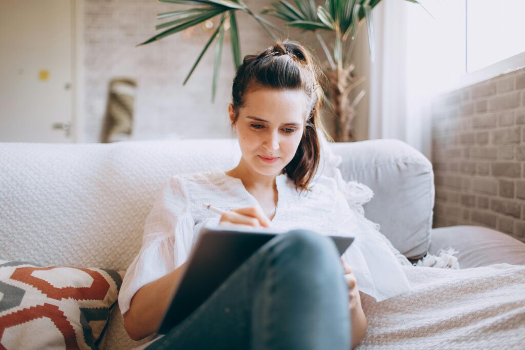 Student sitting on a sofa and using a tablet.