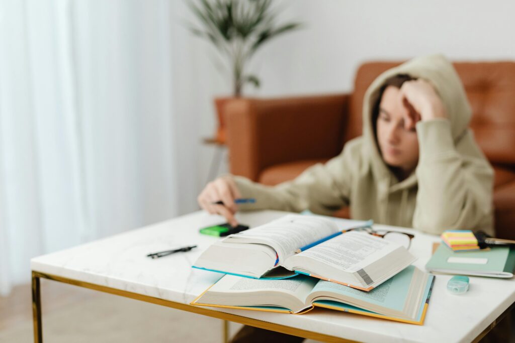 A Boy in Beige Hoodie Studying.