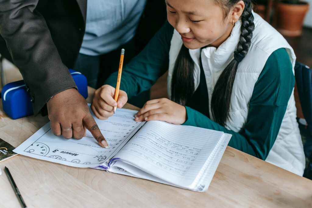 Crop ethnic schoolgirl with teacher during class.