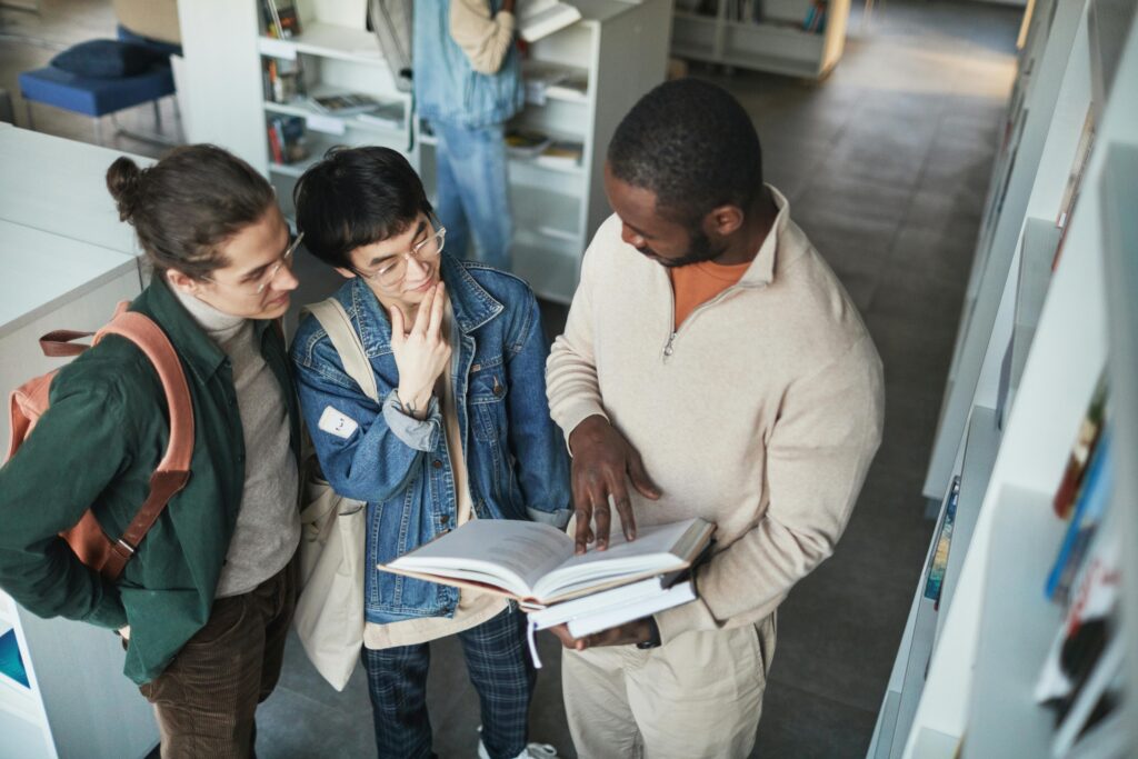 Students in a library looking at a book.