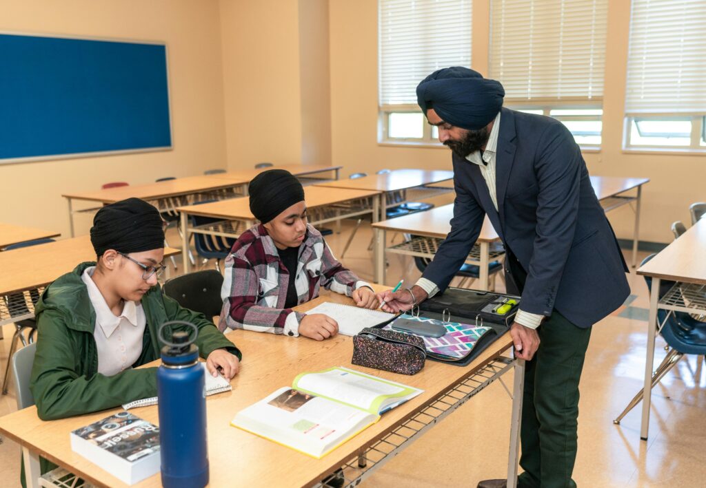 Teacher assisting two female students in a classroom.