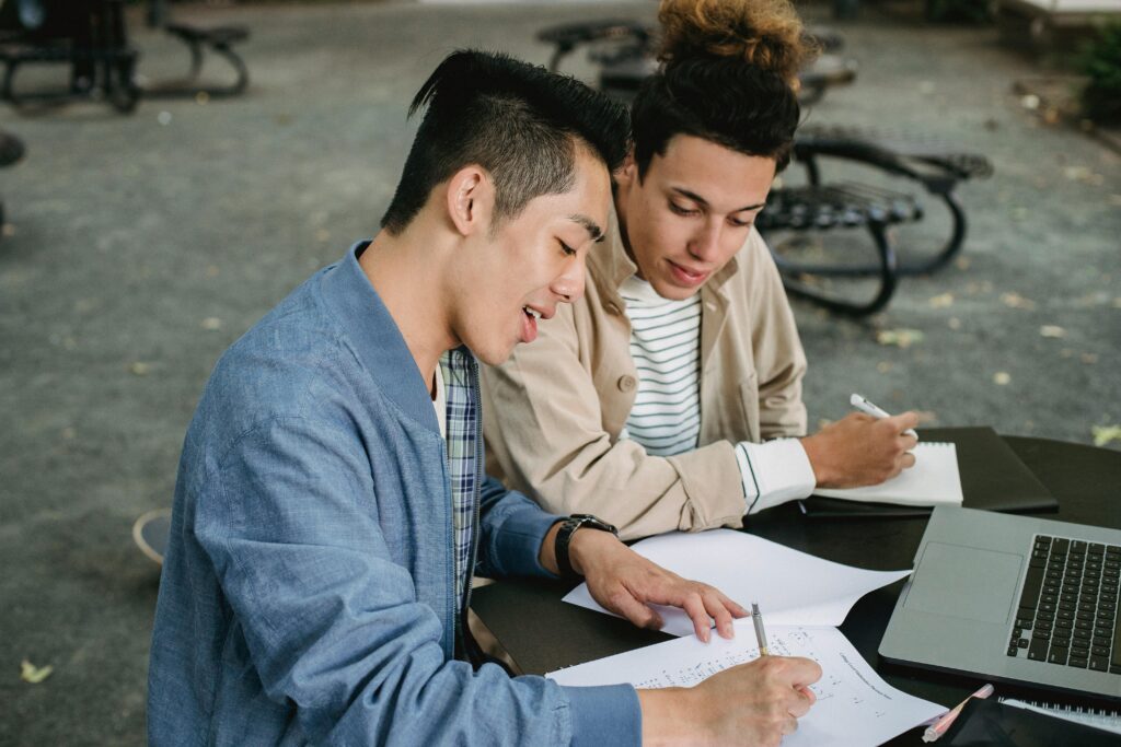 Multiethnic students doing homework together in park.