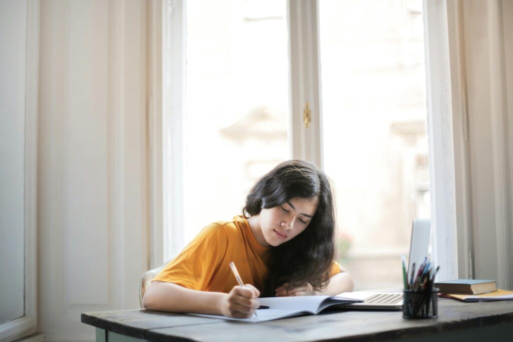 A student in a mustard shirt studying.