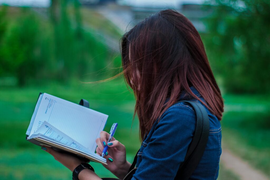 A lady writing on a notebook.